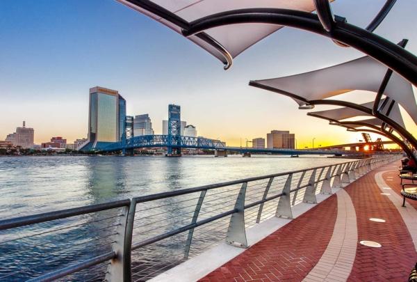 Walkway next to the river with city skyline in the background.